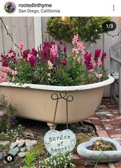 a bathtub filled with lots of flowers next to a sign that says garden of hearts