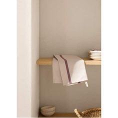 a white towel hanging on a shelf next to plates and bowls in a room with light gray walls