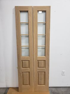 two wooden doors sitting next to each other on top of a floor in front of a white wall