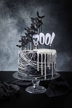 a black and white cake with the word boo on top is sitting on a table