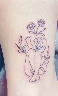 a small tattoo on the side of a woman's leg with flowers and leaves