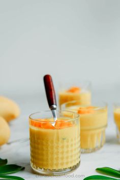 three glasses filled with food sitting on top of a white table next to green leaves