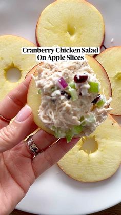 a hand holding an apple slice with a chicken salad on it and the words cranberry chicken salad on apple slices