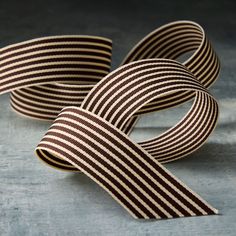 two brown and white striped ribbon laying on top of each other in front of a gray background