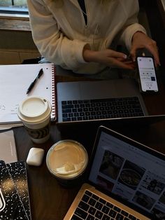 a woman sitting at a table with two laptops and a cup of coffee in front of her