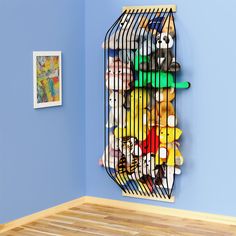 a birdcage filled with stuffed animals on top of a wooden floor next to a blue wall