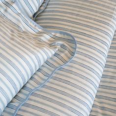 an unmade bed with blue and white striped sheets