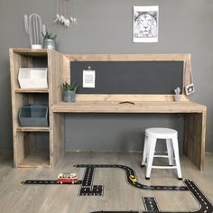 a toy train set sitting on top of a wooden floor next to a desk and shelves