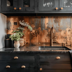 a kitchen with black cabinets, marble counter tops and gold foiled backsplash