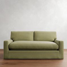 a green couch sitting on top of a wooden floor