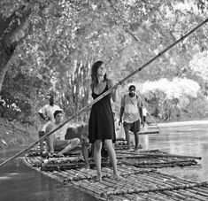 black and white photograph of people on rafts in water with bamboo poles attached to the raft