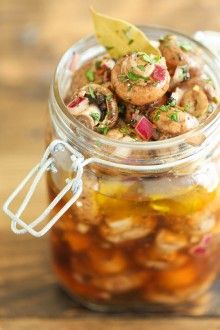 a jar filled with mushrooms and vegetables on top of a wooden table