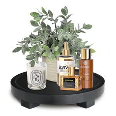 an assortment of skin care products on a black tray next to a potted plant