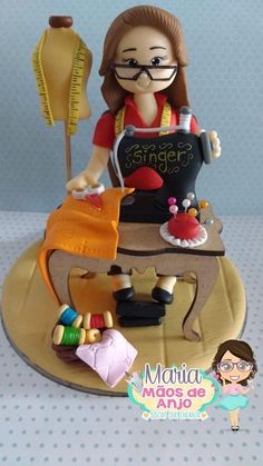 a cake that is shaped like a woman using a sewing machine on top of a table