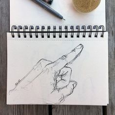 a drawing of a hand holding a pen on top of a notebook next to a ball of yarn