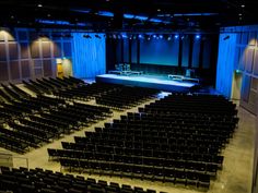 an empty auditorium filled with black chairs