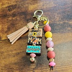 a keychain with beads and tassels on top of a wooden table