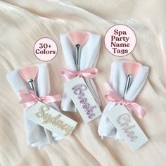 three personalized baby shower tags with pink bows and ribbons on a white bed sheet