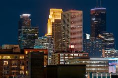 the city skyline is lit up at night, with skyscrapers in the foreground