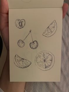 a person holding up a piece of paper with fruit drawn on it