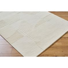 a white rug with squares and lines on the floor in front of a wooden floor