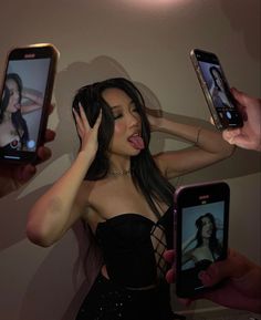 a woman holding two cell phones in front of her face while another person takes a selfie