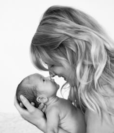 a woman is holding a baby in her lap and kissing it's face with both hands