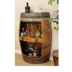 a wooden barrel filled with liquor bottles next to a potted plant