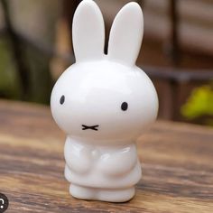 a small white plastic rabbit sitting on top of a wooden table