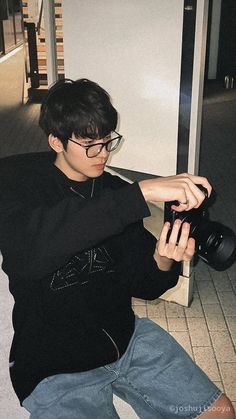 a young man sitting on the ground holding a camera