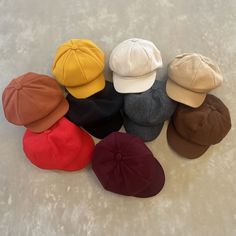 six different colored hats sitting on top of a white surface with no one wearing them