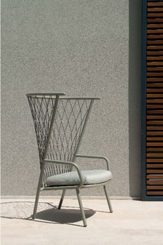 a white chair sitting on top of a cement floor next to a building with shutters