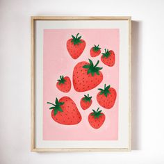 a painting of strawberries on a pink background in a wooden frame hanging on the wall