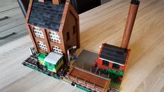 two lego houses sitting on top of a wooden table