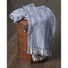 a blue and white blanket sitting on top of an old trunk next to a wooden floor