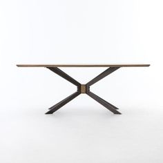 a wooden table sitting on top of a white floor next to a black object with two crossed legs