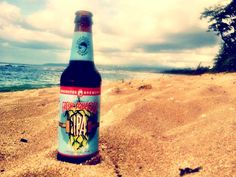 a beer bottle sitting on top of a sandy beach