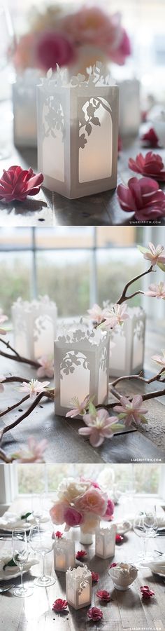 three small white vases sitting on top of a table with pink flowers in front of them