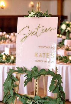 a sign that is on top of a wooden easel with greenery around it