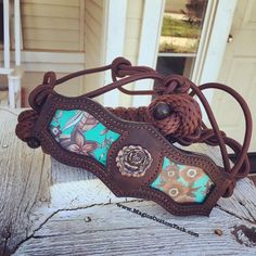 a brown leather purse with blue and green designs on it sitting on a wooden bench