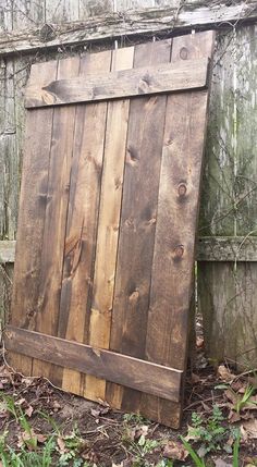 an old wooden door is sitting in the grass next to a fence and some trees