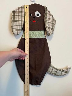 a person is measuring the height of a stuffed dog with a ruler in front of it