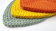 three crocheted dishcloths sitting on top of each other in different colors