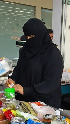 a person wearing a black mask standing in front of a table with food on it