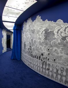 a blue carpeted room with white and black designs on the walls, along with curtains