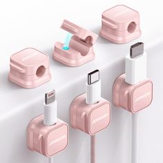 an image of three charging devices connected to each other on a white surface with pink cords and plugs