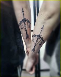 two people are holding hands with tattoos on their arms and one has an arrow in the middle