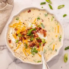 a white bowl filled with soup and topped with bacon, green onions, cheese and sour cream