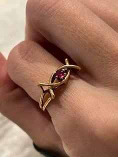 A 9ct gold ruby dress ring.  The ring is hallmarked for Sheffield and date stamped to 1979. There is a pinky red ruby stone surrounded by a decorative gold banded frame, reminiscent of a celtic twist.  Current size N1/2. Approximate weight is 2.4g. This ring comes packaged in our branded Forest & Fox ring boxes which are then securely posted with discreet, unbranded, outer packaging. We can offer resizing for some items for an extra charge (depending on the level of resizing needed), which is at Hallmarked Red Ruby Ring In 14k Gold, Gold Open Ruby Ring In 14k, 14k Gold Ruby Open Ring, Gold Ruby Ring With Open Design, Gold Ruby Birthstone Ring, Gold Ruby Open Ring Birthstone, Gold Ruby Birthstone Open Ring, 14k Gold Hallmarked Ruby Promise Ring, 14k Gold Open Ruby Ring