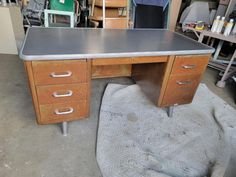 an old wooden desk with metal drawers in a room filled with other furniture and tools